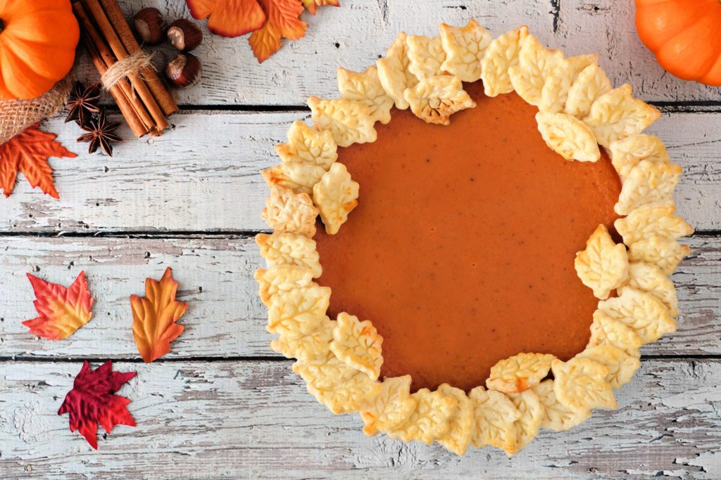 Pumpkin pie with autumn leaf pastry design, above view on white wooden background