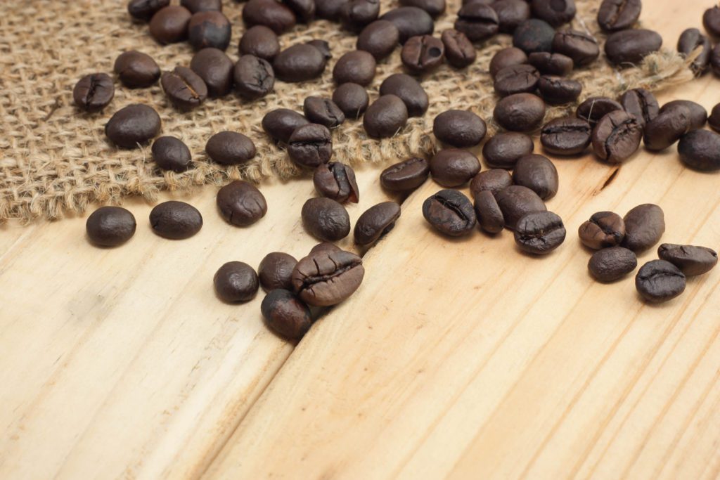Coffee beans on sackcloth and wood background, selective focus.