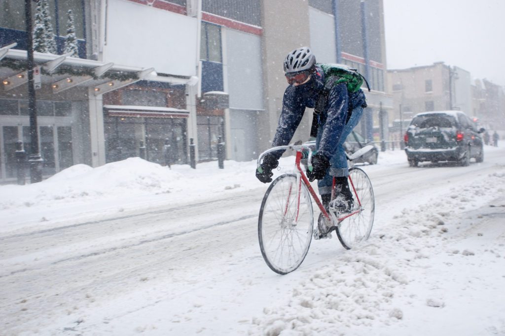 Downtown Montreal bicycle courier delivering letters and parcels during a snow storm.