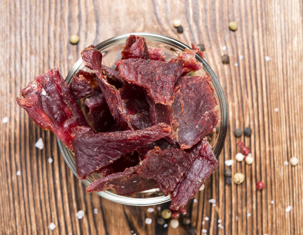 Spicy Beef Jerky on vintage wooden background (close-up shot)