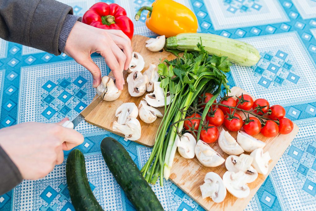 Female hands chopping fresh vegetables on wooden board, close-up