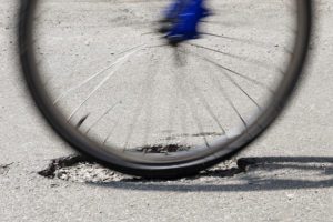 A cyclist rides over a pothole on a road in Kimberley, Nottingham (Photo by Tim Goode/PA Images via Getty Images)