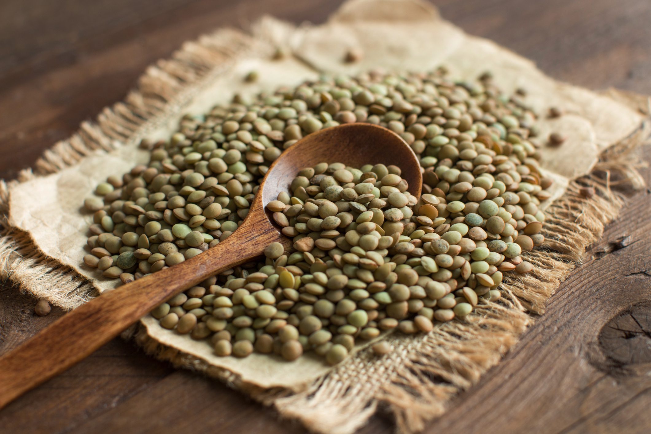 Green lentils with a spoon on a wooden table top view