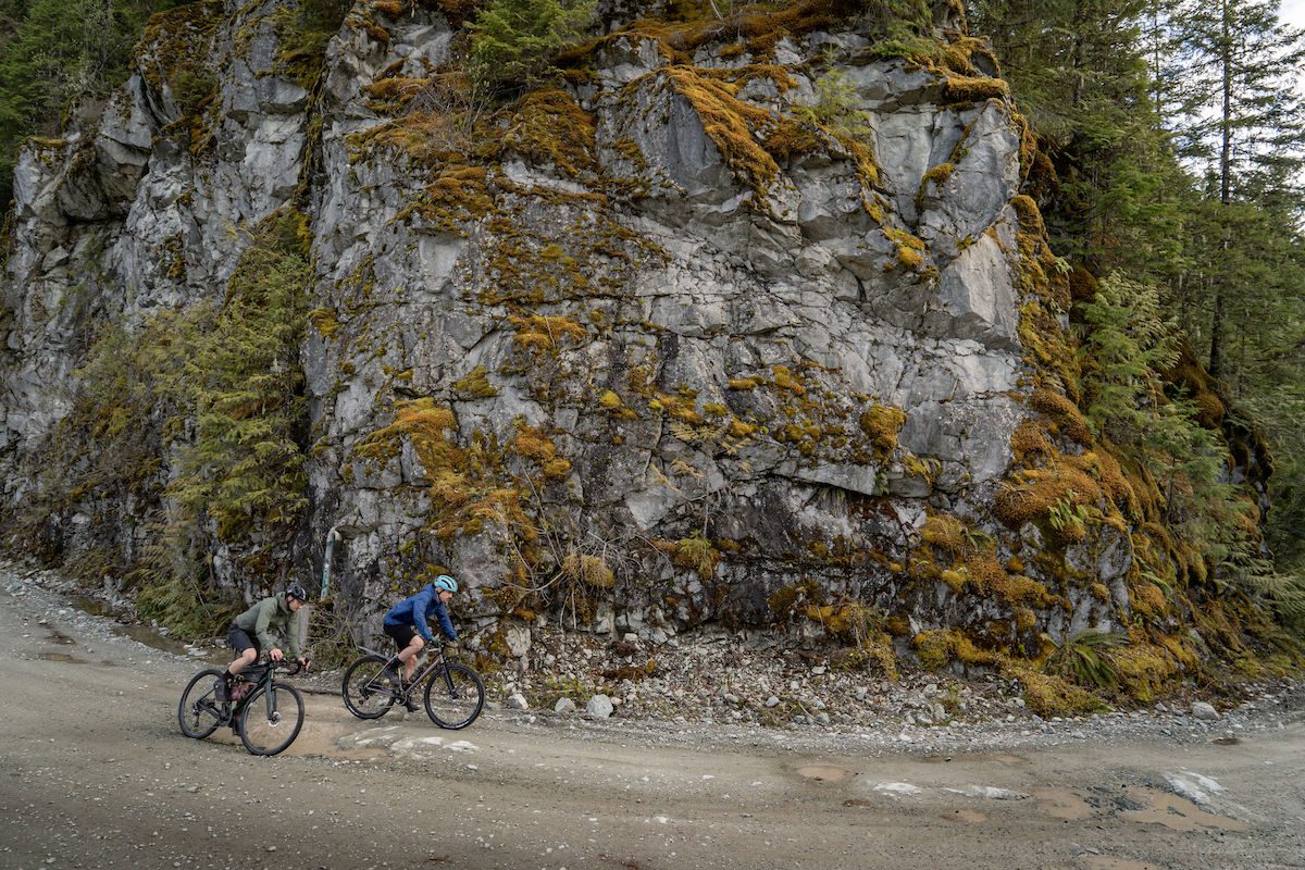 Chris Hatton and Lucas Greenout ride below a rock cliff 