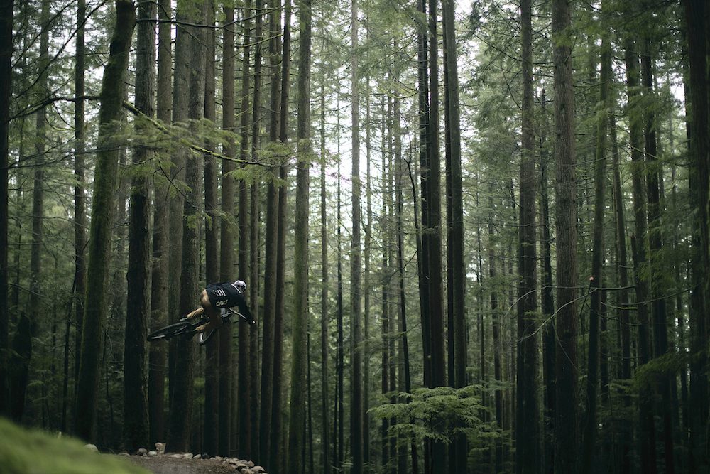 Elliot Jamieson jumps his mountain bike in a forest 