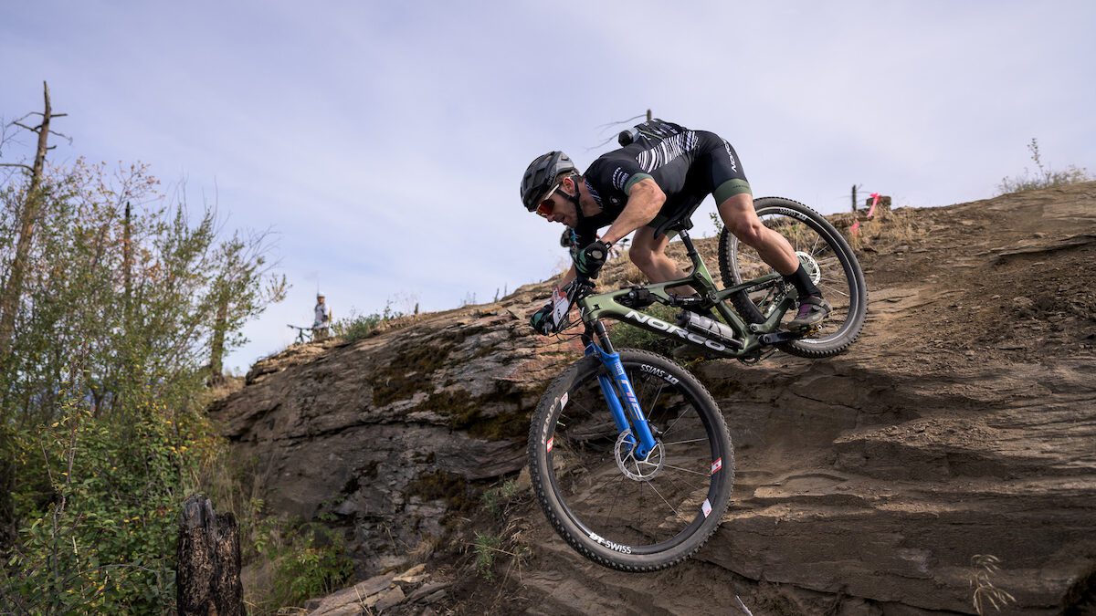 Peter Disera rolls over a steep rock at 2022 BC Bike Race