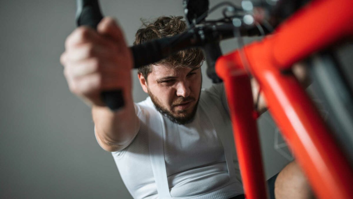 Man shot from below exercising with bicycle at home using a simulation trainer.