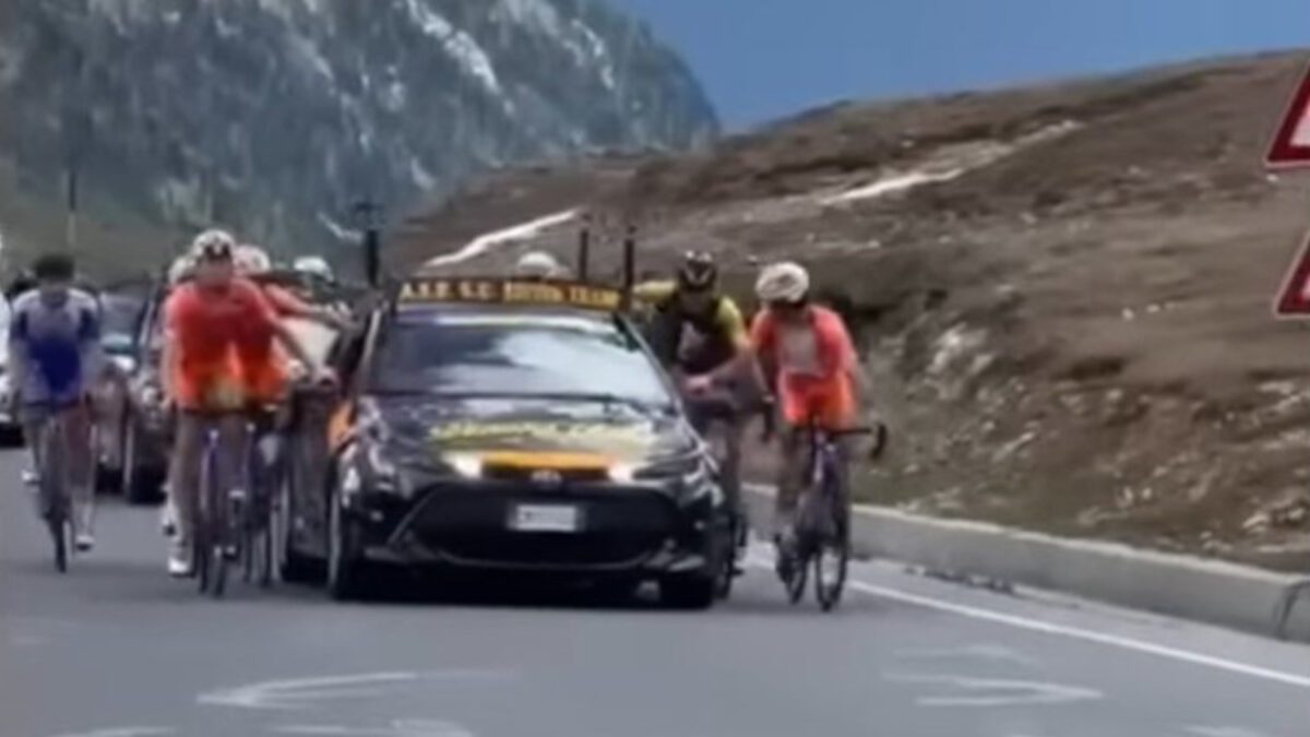 Riders holding onto cars at the Giro Next Gen in Italy