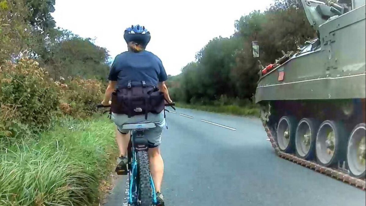 A tank passes a cyclist
