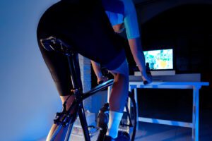 Asian man cycling on the machine trainer he is exercising in the home at night.he play online bike game