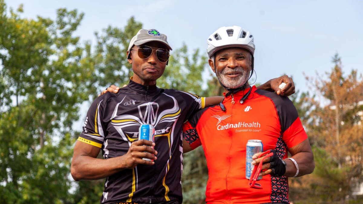 n elderly African American father and his grown up son are wearing cycling shirts in a bike trip